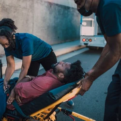 A person being loaded into an ambulance by EMTs and Paramedics