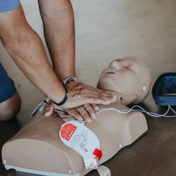 A student performing CPR chest compressions on a manikin.
